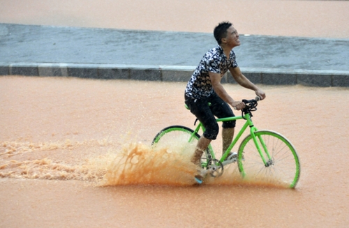 5月11日，一名行人在深圳街頭冒雨騎行。