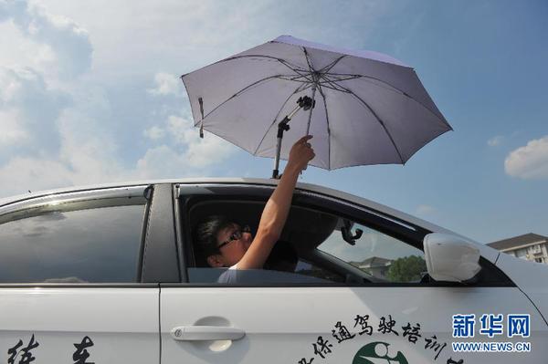 7月20日，在浙江省臨安市一家駕校內，一名學員在車頂架著遮陽傘的教練車內練習。