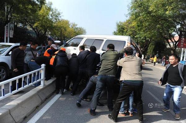 此時周圍路過的市民和附近商販紛紛趕來，十幾人用力抬起面包車，將老人救出。