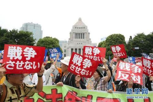 2015年7月14日，日本民眾在國會外集會，手舉標語牌，高喊口號示威，抗議新安保法