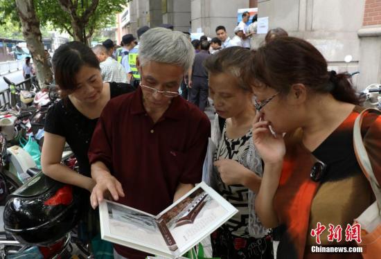 資料圖：幾位杭州市民欣賞已買(mǎi)到的“G20杭州峰會(huì)明信片”。 中新社記者 王剛 攝