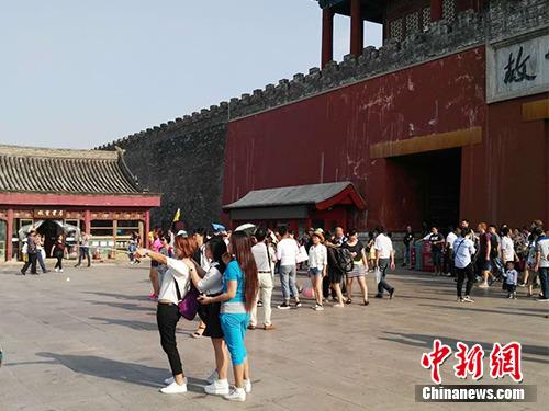 游客在故宮北門外用自拍桿合影。中新網記者 宋宇晟 攝