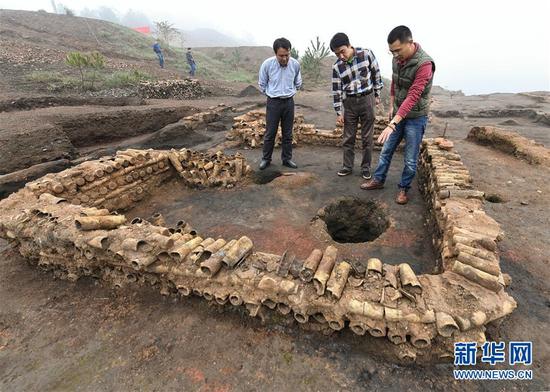 在桐木嶺礦冶遺址，考古人員查看用廢棄坩堝壘筑的房屋遺址（11月18日攝）。