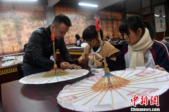 課堂上，嚴(yán)磊手把手地教導(dǎo)學(xué)生如何制作油紙傘。　呂明 攝