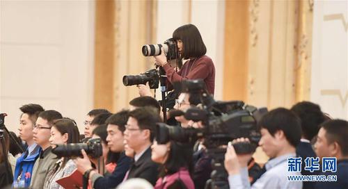 3月7日，一名女記者在十二屆全國人大五次會議江蘇代表團全體會議上采訪拍攝。在兩會會場內外，女代表、女委員、女工作人員、女記者在工作中盡職盡責，展現(xiàn)著自己的風采。 新華社記者陳曄華攝