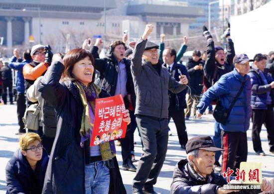 3月10日，在象征著韓國(guó)政治中心的首爾光化門(mén)廣場(chǎng)，民眾在聽(tīng)到憲法法院對(duì)總統(tǒng)樸槿惠彈劾案的審判結(jié)果后歡呼。韓國(guó)憲法法院當(dāng)日作出裁決，宣布彈劾案成立。樸槿惠成為韓國(guó)歷史上首位被彈劾罷免的總統(tǒng)。<a target='_blank' href='http://www.chinanews.com/'>中新社</a>記者 吳旭 攝