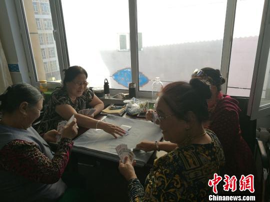 圖為進(jìn)城牧民在一起打撲克?！±類燮?攝