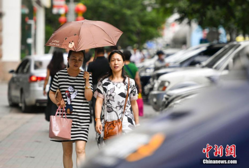 新疆烏魯木齊市街頭，民眾打傘抵擋高溫天氣。