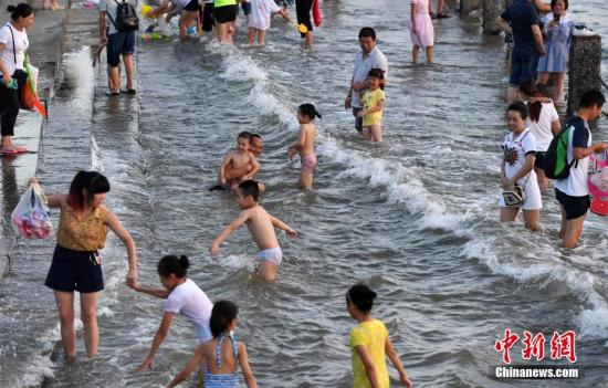 7月4日傍晚，市民們帶著小孩在海邊戲水消暑。連日來，受副熱帶高壓影響廈門地區(qū)持續(xù)高溫。 張斌 攝