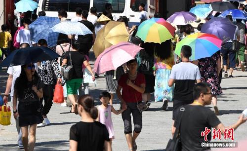 7月12日，廈門一景點游客們紛紛打起傘遮擋烈日。張斌 攝