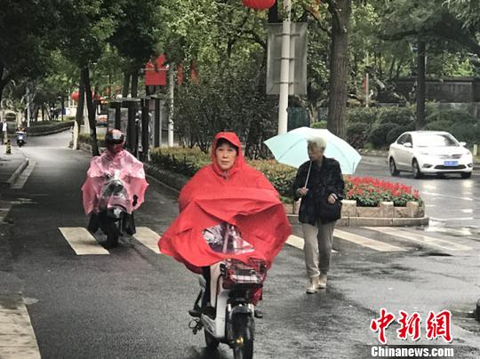 11日，南京迎來降溫降雨。圖為市民披上雨衣出行?！铑伌?攝