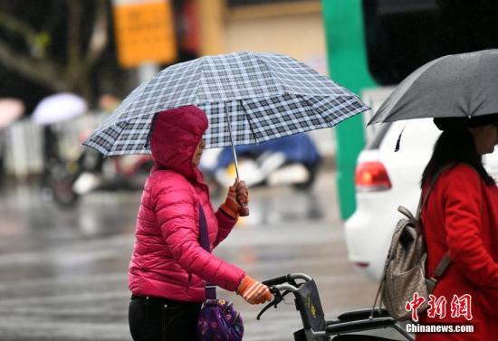資料圖：昆明市區(qū)里身著羽絨服冒雨趕路的民眾。 中新社記者 李進(jìn)紅 攝