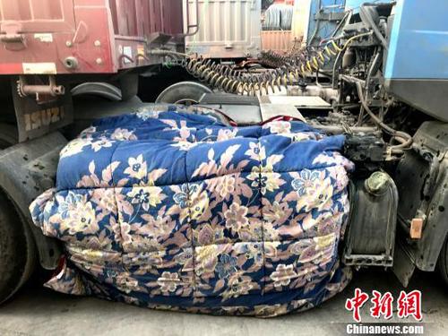 圖為卡車司機(jī)用棉被為卡車“取暖”?！＄娦?攝