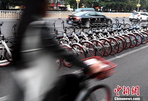 資料圖：路人騎著共享單車經過“車堆”。<a target='_blank' href='http://www.chinanews.com/'>中新社</a>記者 張斌 攝