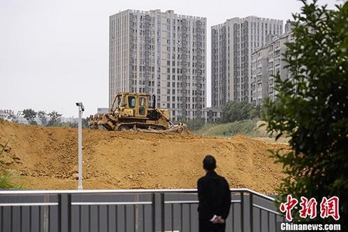 市民觀望湖南長沙一樓盤工地上的推土機(jī)作業(yè)。 <a target='_blank' href='http://www.chinanews.com/'>中新社</a>記者 楊華峰 攝