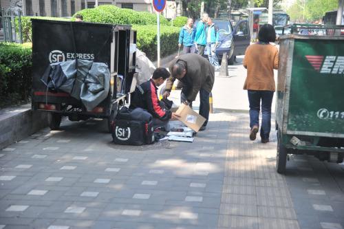 圖為快遞小哥在路邊配送快遞。呂春榮 攝