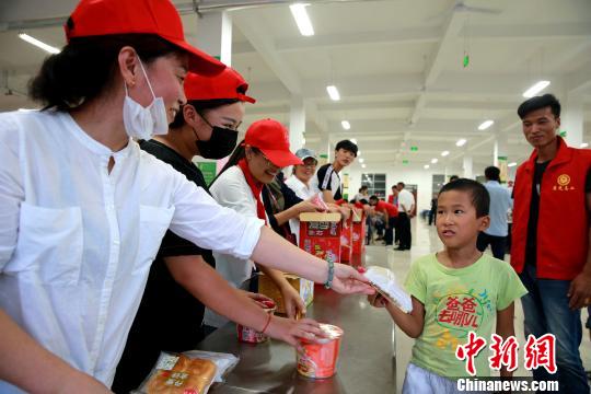 8月24日，志愿者在濰坊壽光市營(yíng)里鎮(zhèn)第二初級(jí)中學(xué)安置點(diǎn)為災(zāi)民發(fā)放救援物資?！×籂?攝