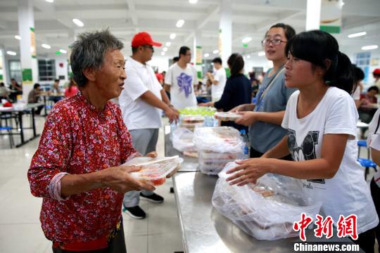 8月24日，志愿者在濰坊壽光市營(yíng)里鎮(zhèn)第二初級(jí)中學(xué)安置點(diǎn)為災(zāi)民發(fā)放救援物資。　梁犇 攝