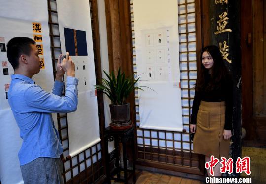 一名“90后”女大學(xué)生篆刻作者在自己創(chuàng)作的作品前留影?！∮浾邉⒖筛?攝