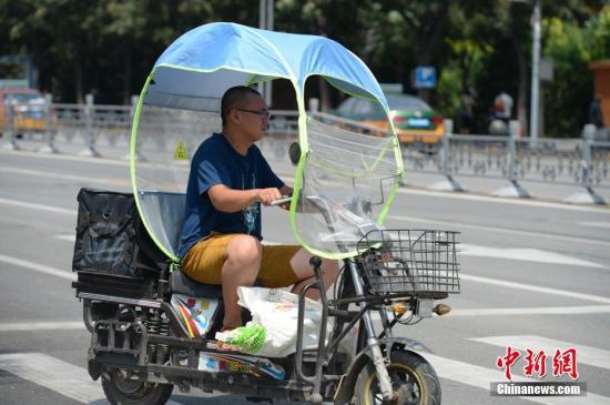 資料圖：男子在電動車上撐起遮陽棚。<a target='_blank' href='http://www.chinanews.com/'>中新社</a>記者 劉文華 攝