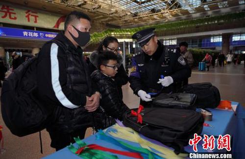 12月28日，北京西站派出所民警為背黑色雙肩包的旅客系上個(gè)性小標(biāo)識(shí)，以防在通過(guò)安檢或乘車過(guò)程中出現(xiàn)錯(cuò)拿情況。(完) 龐賀雷 攝