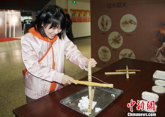 參觀者現(xiàn)場體驗(yàn)“鉆木取火”?！⌒烨擅?攝