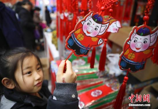 1月23日，正在北京全國農(nóng)業(yè)展覽館舉辦的2019老北京年貨大集人頭攢動、熱鬧非凡。全國各地區(qū)優(yōu)質(zhì)特色產(chǎn)品及民俗文化在此一一呈現(xiàn)，給北京市民帶來精彩紛呈的購物體驗。圖為小女孩被年貨大集上的豬年福牌吸引。<a target='_blank' href='http://www.chinanews.com/'>中新社</a>記者 趙雋 攝