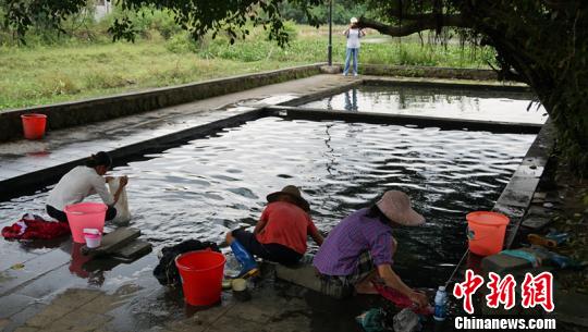 幾名婦女在“雅蔡冷泉”旁一邊聊天一邊洗著衣物。　符宇群 攝