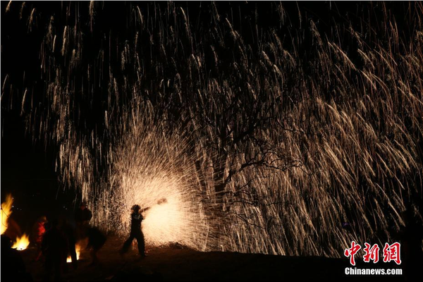 該村“打樹花”的習(xí)俗已延續(xù)了近600年，村民將生鐵融成鐵水后，再用特制的木板將鐵水擊打至樹上，頓時(shí)綻放出萬點(diǎn)“鐵花”。中新社記者 陳昊 攝