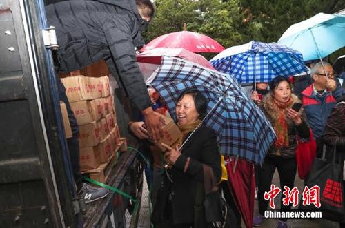 資料圖：上海百名居民在雨中排成一條長(zhǎng)龍，領(lǐng)取剛到貨的秭歸臍橙。供圖