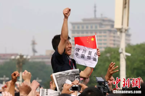 2008年5月19日，北京天安門廣場(chǎng)上的民眾為地震遇難者默哀，一位來自四川的男子高舉右手為家鄉(xiāng)加油。中新社記者 富田 攝