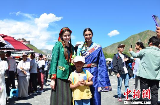 圖為身著藏族服裝的外籍模特比賽完與當(dāng)?shù)氐男『⒑嫌傲裟睢！◆數(shù)り?攝