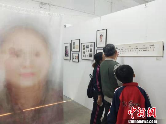 在第19屆中國平遙國際攝影大展柴油機展區(qū)的一角，一張大幅的人像彩畫吸引來往游客駐足拍照。　楊佩佩 攝