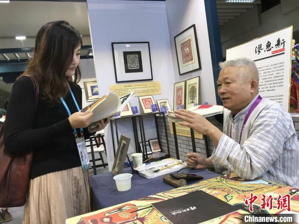 秀洲農(nóng)民畫畫家繆惠新和參觀者交流。供圖