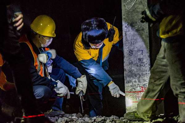 機械工隊長侯寧與03506清篩車組車隊長核對清篩后的線路標高，嚴把施工質(zhì)量關(guān)。（攝影 賈佳）