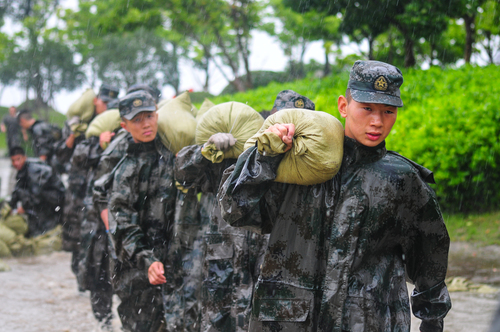 圖為在安徽合肥巢湖任務(wù)區(qū)官兵在暴雨中扛運沙袋，加固堤壩。（王文洲 攝）