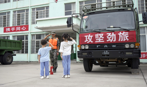 圖為在學(xué)校宿營點，小學(xué)生向抗洪官兵官兵敬禮表達謝意的畫面。（付少旋）
