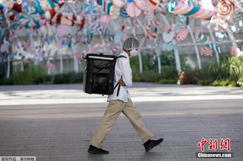 資料圖：當?shù)貢r間2021年1月4日，泰國曼谷，一名快遞員“全副武裝”走在街頭。